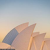 australia stock photography | Sydney Opera House Sails at Sunrise, Sydney, NSW, Australia, Image ID AU-SYDNEY-OPERA-HOUSE-0048. The Sydney Opera House is renowned for its striking sail-like shells, which are emblematic of its innovative design and architectural brilliance. These shells, constructed from a series of precast concrete panels, evoke the image of billowing sails catching the wind, symbolising both movement and fluidity. Arranged in a graceful formation, the shells create a sense of harmony with their surroundings, while their gleaming white surface reflects the changing light throughout the day. This iconic feature not only enhances the visual impact of the structure but also serves as a testament to the vision of architect Jorn Utzon, who sought to merge the building with the natural beauty of Sydney Harbour, making it a masterpiece of modern architecture. The photo showcases the iconic Sydney Opera House, bathed in the warm, golden light of sunrise. Its distinctive sail-like shells glow against the soft pastel colours of the morning sky, creating a striking contrast with the calm waters of Sydney Harbour. The sun's rays gently illuminate the building's unique architecture, emphasising its graceful curves and lines. This enchanting moment captures the beauty and elegance of one of the world's most recognisable landmarks, inviting viewers to experience the serenity and majesty of this iconic location.