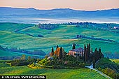  stock photography | Podere Belvedere at Dawn, Pienza, Val d'Orcia, Tuscany, Italy, Image ID ITALY-TUSCANY-0012. A tranquil view of Podere Belvedere in Pienza, Tuscany, captured just before sunrise. The farmhouse sits gracefully atop a hill, surrounded by cypress trees and rolling fields. Morning fog layers the distant hills, creating a soft, dreamy atmosphere. The muted light of dawn enhances the serenity of the scene, highlighting the gentle textures of the landscape and evoking the timeless charm of the Tuscan countryside.