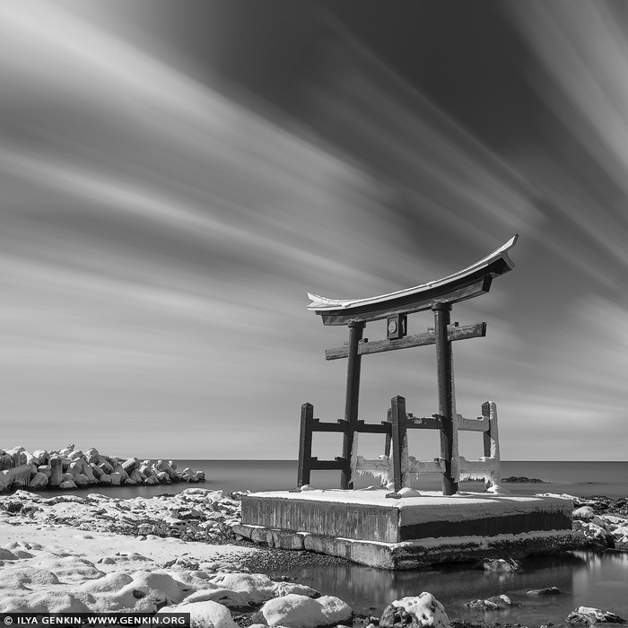 portfolio stock photography | Torii Gate of the Toyosaki Konpira Shrine, Shosanbetsu, Hokkaido, Japan. The Torii Gate of the Toyosaki Konpira Shrine in Shosanbetsu, Hokkaido, Japan, is a striking symbol of spiritual passage and cultural heritage. Perched along the coastline with the Sea of Japan as its backdrop, the vibrant vermilion gate creates a captivating contrast against the deep blue waters and the wide expanse of sky. This Torii, standing as a sentinel to the sacred grounds beyond, frames breathtaking views. The location's serene and remote setting adds to the shrine's tranquil atmosphere, inviting visitors to pause and reflect amid the harmony of nature and spirituality. The site is particularly enchanting during the golden hours of sunrise or sunset, when the gate is bathed in warm light, amplifying its timeless beauty and the profound sense of connection to the surrounding landscape.