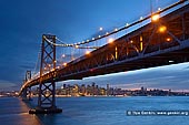 usa stock photography | Oakland Bay Bridge at Sunset, San Francisco Bay, California, USA, Image ID US-SAN-FRANCISCO-BAY-BRIDGE-0001. The San Francisco-Oakland Bay Bridge (known locally as the Bay Bridge) is a pair of bridges spanning San Francisco Bay of California, in the United States. The bridge consists of two main spans of roughly equal length, a western span connecting downtown San Francisco to Yerba Buena Island and an eastern span connecting the island to Oakland. The view to San Francisco from Treasure Island or from Yerba Buena Island is incomparable.